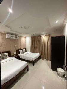 una camera d'albergo con due letti e una finestra di الجناح الأبيض للأجنحه الفندقية a Dammam