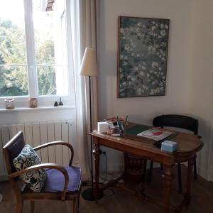 uma secretária com um candeeiro e uma cadeira ao lado de uma janela em Le Clos 25 em Chalon-sur-Saône