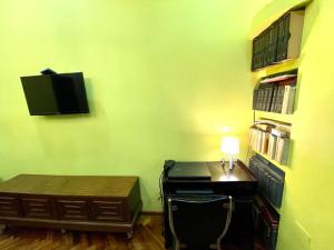 Habitación con escritorio y TV en una pared verde. en Old Batumi Apartment en Batumi