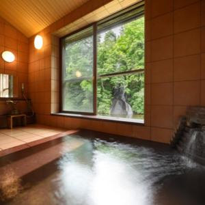 Habitación con baño con ventana y piscina en Namari Onsen Kokoro No Toki Jusangatsu, en Hanamaki