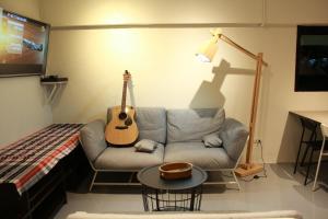 a living room with a couch with a guitar on the wall at Jam Hostel Bangkok in Bangkok