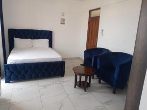 1 dormitorio con cama, sofá azul y sillas en Amber Apartment en Mombasa
