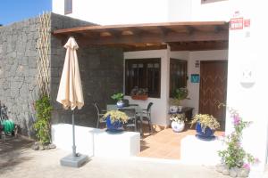 eine Terrasse mit einem Sonnenschirm, einem Tisch und Stühlen in der Unterkunft Villa Panoramica in Yaiza