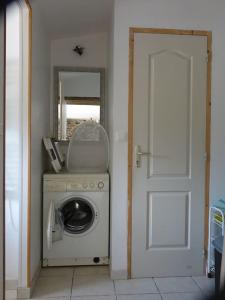 a laundry room with a washing machine and a door at Charmante longère près des côtes Finistériennes in Plouégat-Guérand