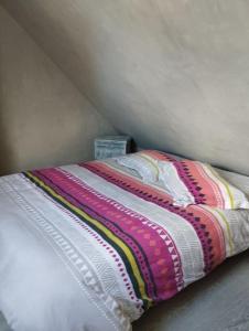 a bed with a colorful blanket on top of it at Charmante longère près des côtes Finistériennes in Plouégat-Guérand