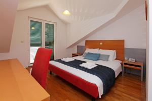- une chambre avec un grand lit et une chaise rouge dans l'établissement Apartments Vala, à Vela Luka