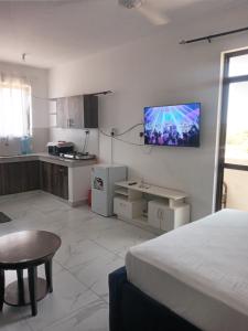 Habitación con cama y cocina con TV en la pared. en Amber Apartment, en Mombasa