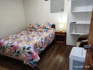 a small bedroom with a bed with a colorful comforter at Hospedaje Lago Llanquihue in Llanquihue