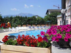 vistas a una piscina con flores y sillas en Hotel Bellaria, en Levico Terme