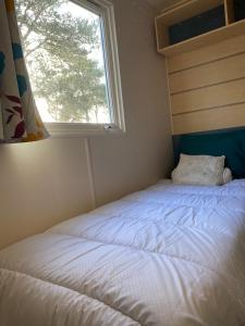 Cama en habitación pequeña con ventana en Camping Cœur De Vendée, en La Boissière-de-Montaigu