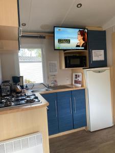 cocina con nevera y TV de pantalla plana. en Camping Cœur De Vendée, en La Boissière-de-Montaigu