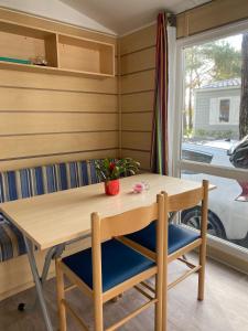 mesa y sillas en una habitación con ventana en Camping Cœur De Vendée, en La Boissière-de-Montaigu