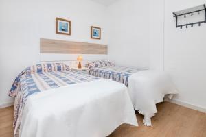Duas camas num quarto com paredes brancas e pisos de madeira em BHost - El Indiano em Córdoba