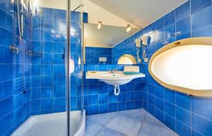 a blue tiled bathroom with a sink and a shower at Residenza D'epoca La Corallina in Castellabate