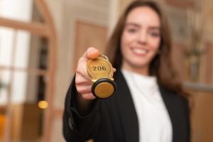 a woman is holding up a key in her hand at Hotel Residence in Würzburg