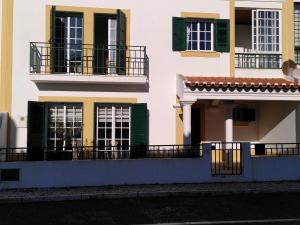 ein Gebäude mit grünen Rollläden und Balkonen darauf in der Unterkunft BRIGHT AMBIENCE by Stay in Alentejo in Vila Nova de Milfontes