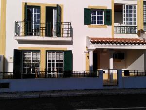 un edificio con persianas verdes y balcones. en BRIGHT AMBIENCE by Stay in Alentejo, en Vila Nova de Milfontes