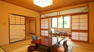 a room with a table and chairs and windows at Fujisan Ryokan in Hanamaki