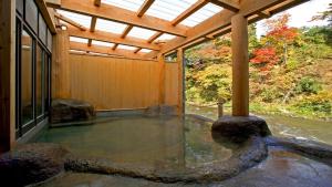 a hot tub inside of a house with a wooden ceiling at Fujisan Ryokan in Hanamaki