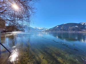 a view of a body of water with snow covered mountains at Waterfront Apartments Zell am See - Steinbock Lodges in Zell am See