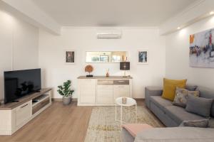 a living room with a couch and a tv at Apartamento Sunset on the Sea in Albufeira