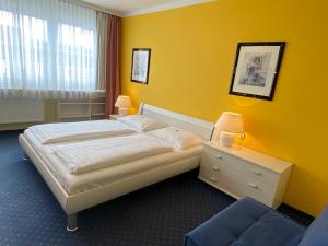 a yellow bedroom with a bed and a chair at Gasthof Großmann in Heidenreichstein