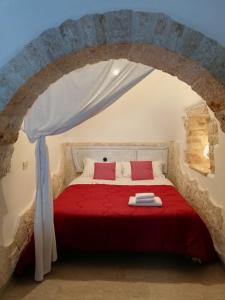- une chambre avec un lit rouge dans un mur en pierre dans l'établissement Luxury Trulli sabotino, à Alberobello