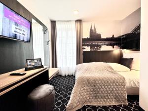 a hotel room with a bed and a flat screen tv at Rhein Hotel St. Martin in Cologne