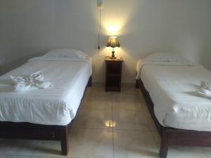 ムンドゥックにあるAdila Warung and Homestayのベッドルーム1室(白いシーツとランプ付きのベッド2台付)