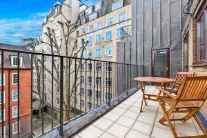 einen Balkon mit einem Holztisch und einem Holzstuhl in der Unterkunft Tavistock Place Apartments in London