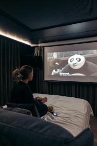 Kobieta siedząca na łóżku oglądająca film w obiekcie Sogndal Fjordpanorama - The view w mieście Sogndal