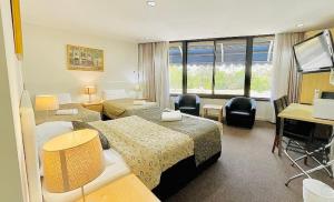 a hotel room with two beds and a television at Connells Motel & Serviced Apartments in Traralgon