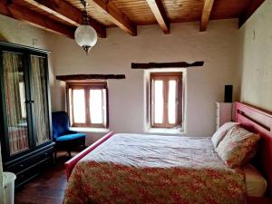 a bedroom with a bed and a chair and windows at Acogedora casa del siglo XIX 