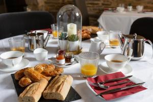 een tafel met brood, koffie en drankjes erop bij La Metairie-du-Vauhariot - Lodge ou Chambre - Piscine Chauffée - Vue Mer et Mont Saint Michel - GR34 - Résidence Hôtelière in Cancale