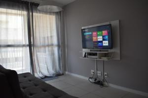 a living room with a couch and a flat screen tv at Mediterrâneo 507 - Todo Equipado, Ar Condicionado, Churrasqueira na Varanda, Internet Fibra 600MB, Estacionamento Grátis in Cabo Frio