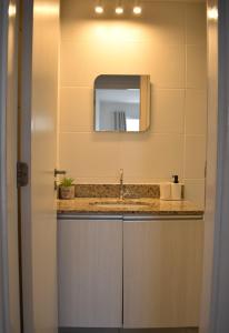 a bathroom with a sink and a mirror at Mediterrâneo 507 - Todo Equipado, Ar Condicionado, Churrasqueira na Varanda, Internet Fibra 600MB, Estacionamento Grátis in Cabo Frio