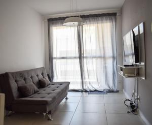 a living room with a couch and a large window at Mediterrâneo 507 - Todo Equipado, Ar Condicionado, Churrasqueira na Varanda, Internet Fibra 600MB, Estacionamento Grátis in Cabo Frio