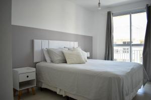 a white bedroom with a large bed and a window at Mediterrâneo 507 - Todo Equipado, Ar Condicionado, Churrasqueira na Varanda, Internet Fibra 600MB, Estacionamento Grátis in Cabo Frio