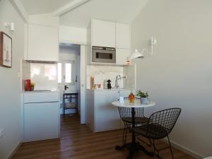 a kitchen with white cabinets and a table and chairs at Maria da Sé Historic House in Porto