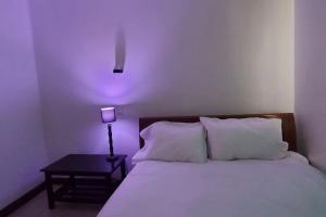 1 dormitorio con cama blanca y mesita de noche con lámpara en 2 bedroom Apt 20 min to JKIA Airport,SGR Train St., en Athi River