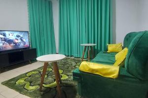 a living room with a green couch and a tv at 2 bedroom Apt 20 min to JKIA Airport,SGR Train St. in Athi River