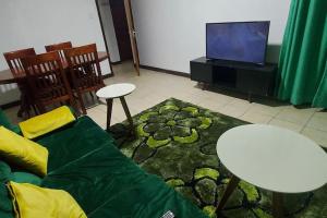 a living room with a couch and a table and a tv at 2 bedroom Apt 20 min to JKIA Airport,SGR Train St. in Athi River