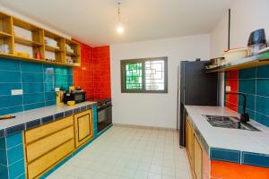 a large kitchen with blue and red tiles at Résidence Decamaret Warang in Ouoran