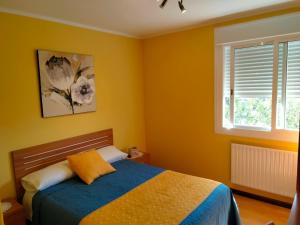 a bedroom with a bed with yellow walls and a window at Hostal Nuevo Alonso in Bembribe