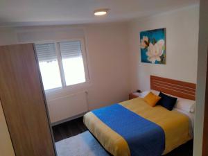 a bedroom with a bed with a blue and yellow blanket at Hostal Nuevo Alonso in Bembribe