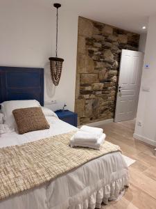 1 dormitorio con 1 cama grande y pared de piedra en Caraxolas, en Lugo