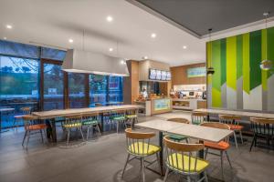 a dining room with tables and chairs and a kitchen at Holiday Inn Express Emei Mountain by IHG in Emeishan