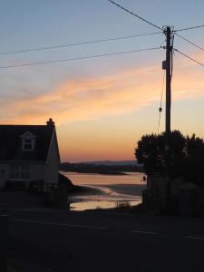a house with a view of the ocean at sunset at Village Way Apartments in Kincasslagh
