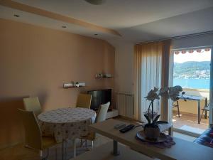 a living room with a table and chairs and a room with a window at More in Rab