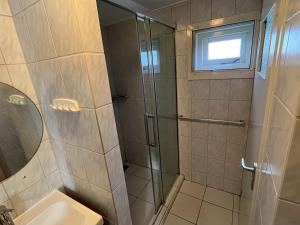 a bathroom with a shower with a toilet and a window at Gezellige bungalow op steenworp afstand van het strand in Ouddorp +15 photos